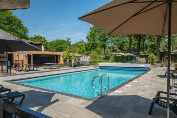 Verwarmd buitenzwembad met ligstoelen en parasols